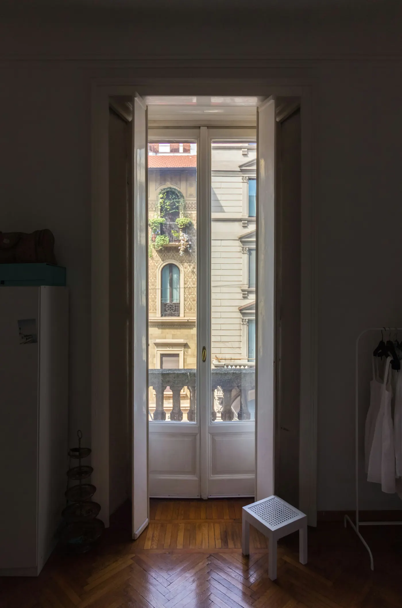 A tall glass balcony door in an old apartment, looking onto a period facade